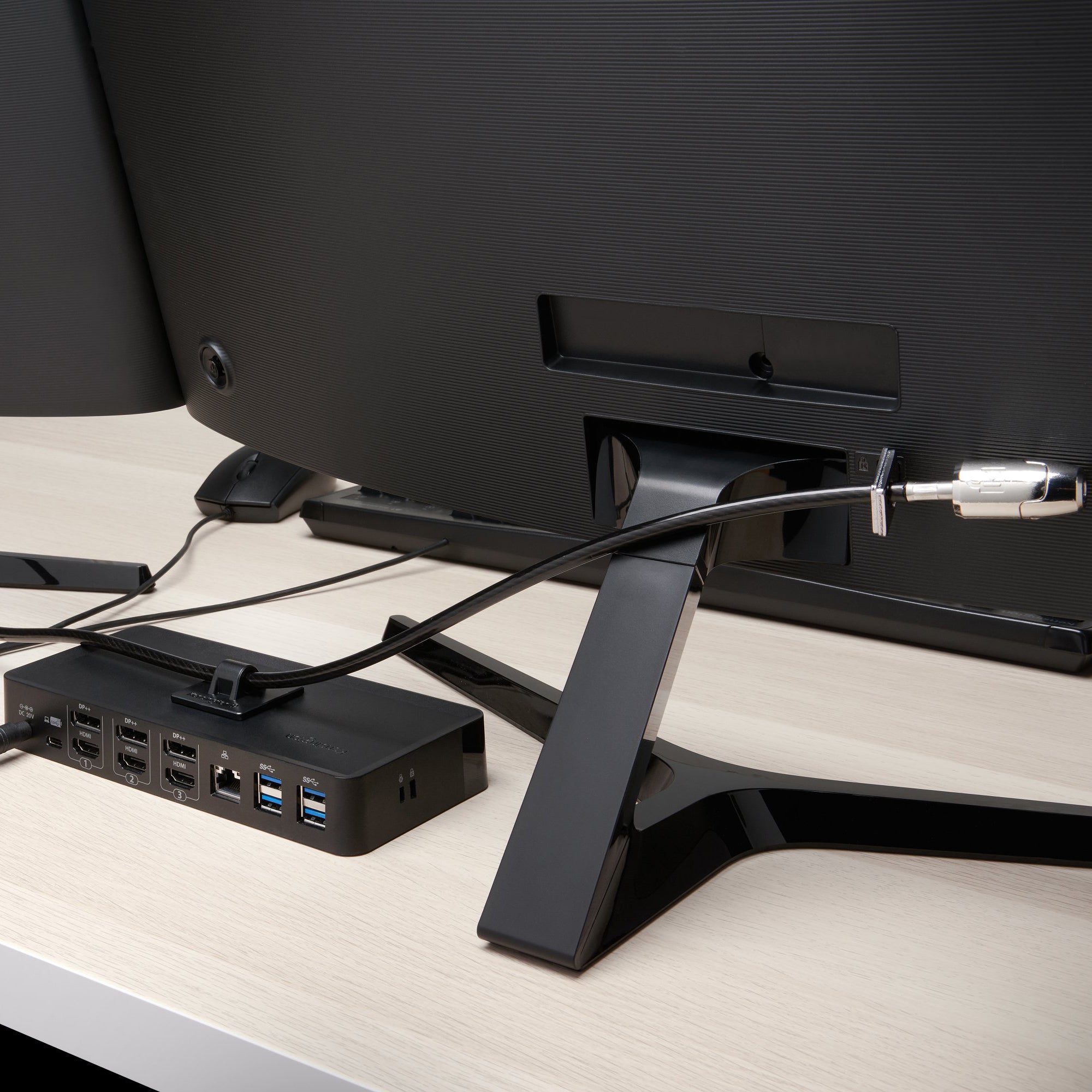 Rear monitor setup showing the Kensington security cable connected to a display and docking station. The image highlights how the locking system secures valuable workplace equipment while maintaining a clean and organised desk layout.