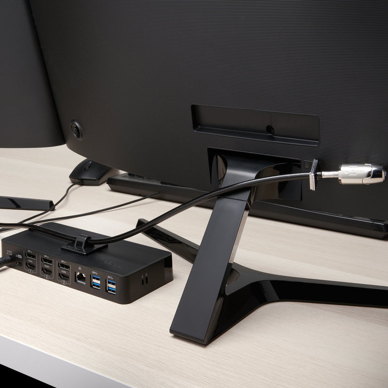Rear monitor setup showing the Kensington security cable connected to a display and docking station. The image highlights how the locking system secures valuable workplace equipment while maintaining a clean and organised desk layout.