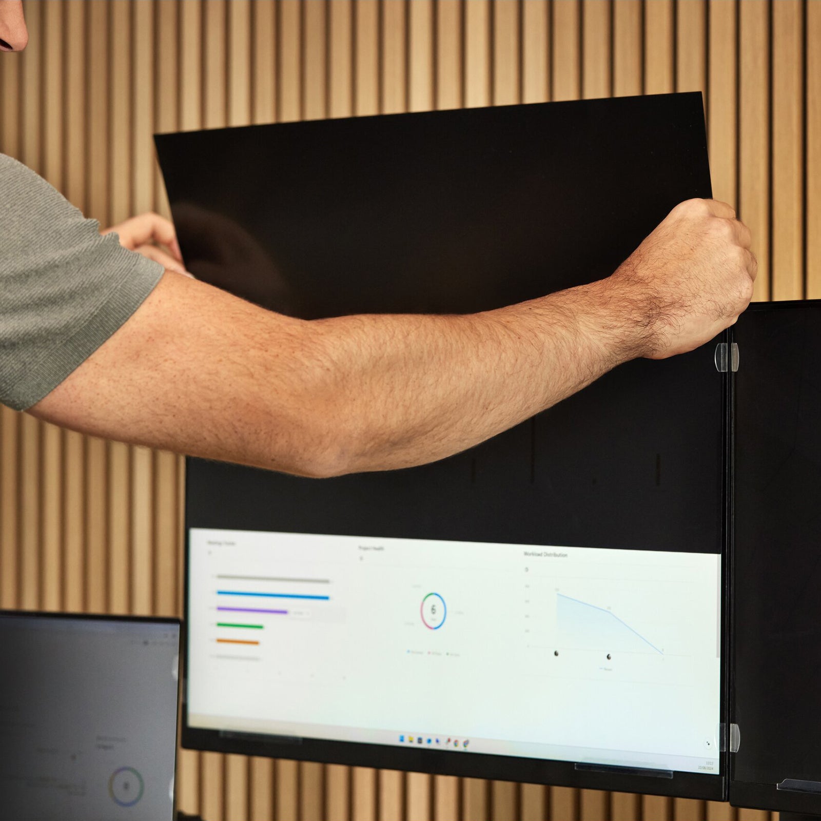 Close up view of the privacy filter being attached to an ultrawide monitor. The image shows the screen remaining visible from the front while the privacy filter darkens visibility from side angles for enhanced data protection.