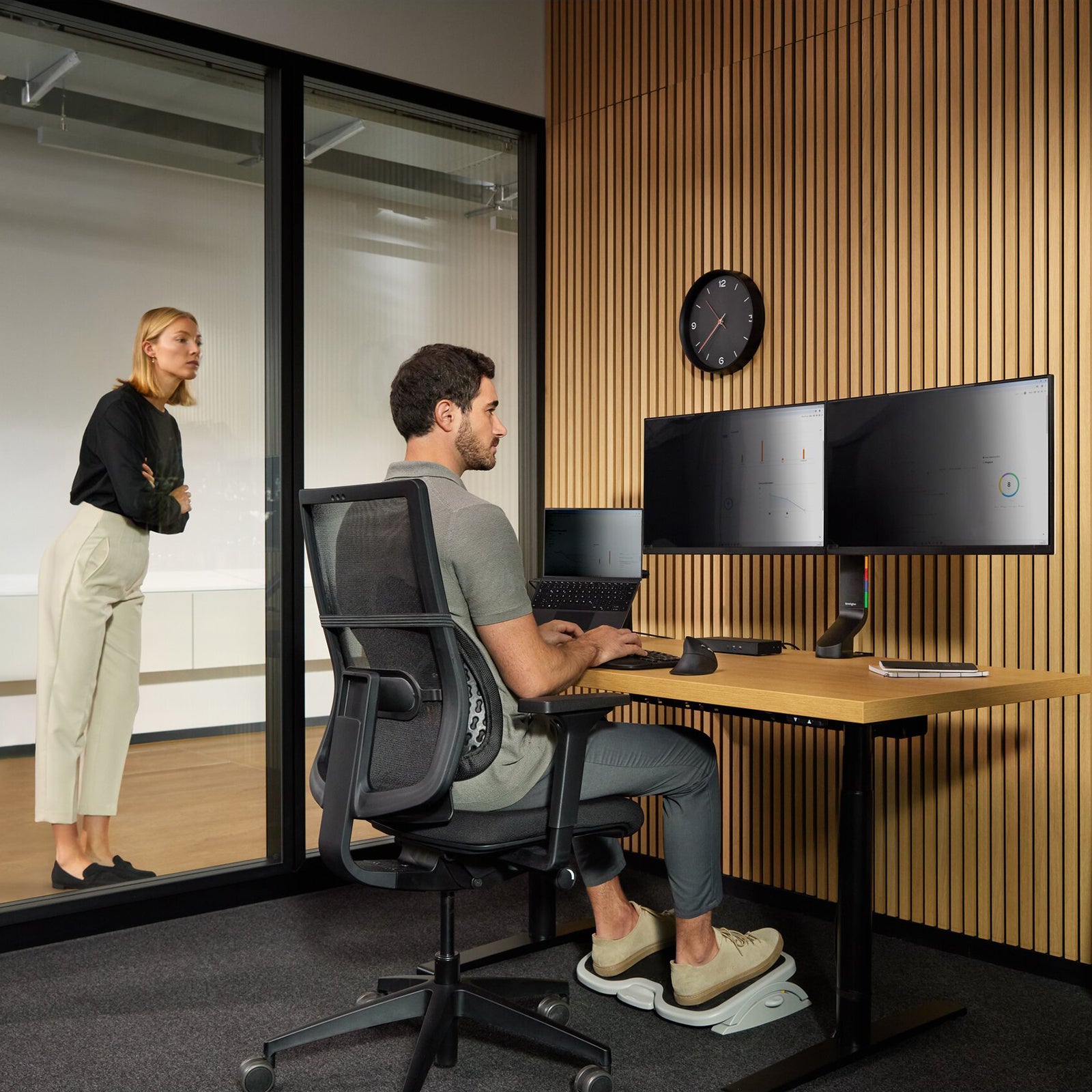 Professional office workstation featuring a 34 inch ultrawide monitor fitted with a Kensington privacy screen. The display remains visible to the seated user while limiting side visibility, demonstrating privacy protection in an open office environment with dual monitors and ergonomic accessories.