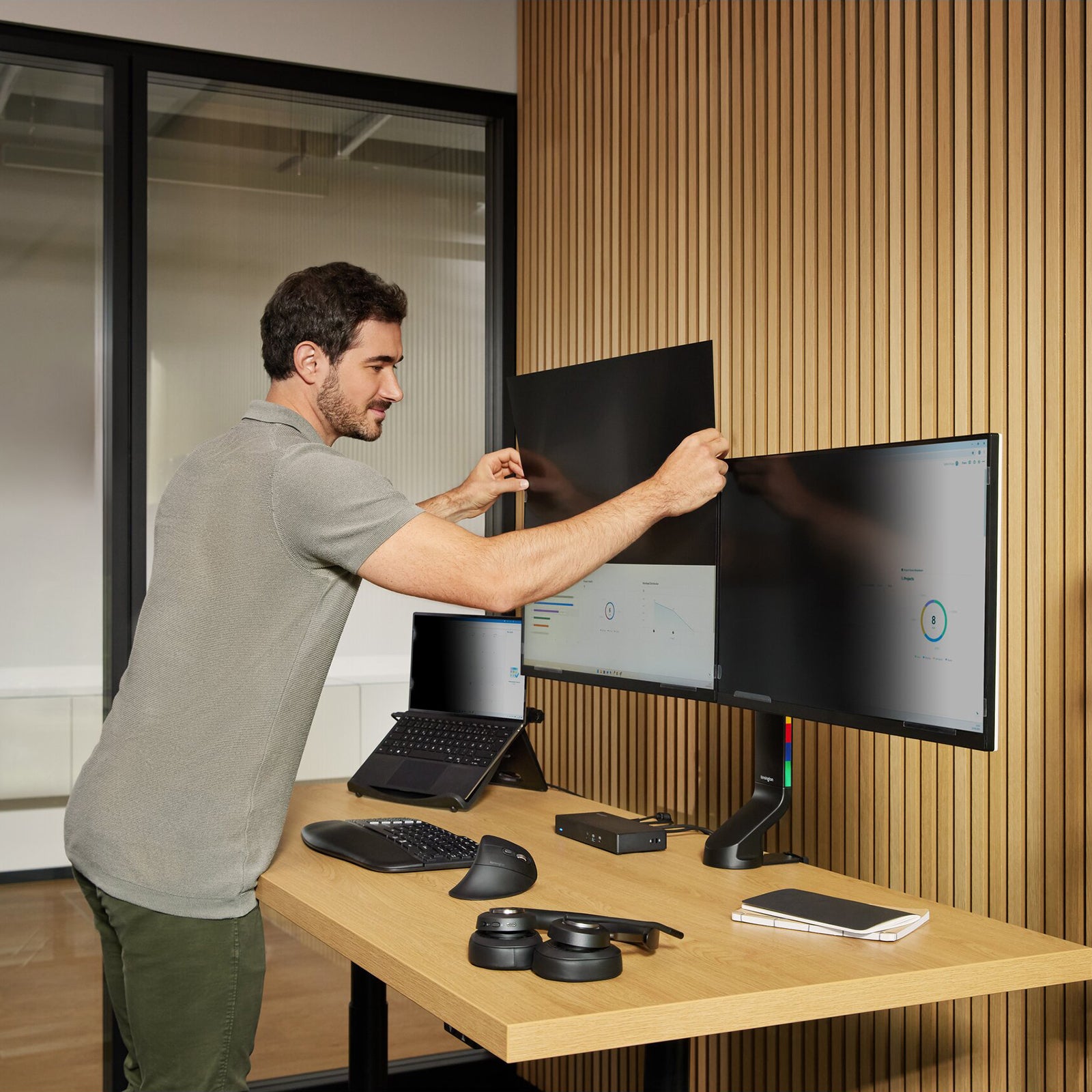 User installing a Kensington privacy screen onto a 34 inch ultrawide monitor at a modern workstation. The image highlights the simple application process and secure fit designed for widescreen 21:9 displays.