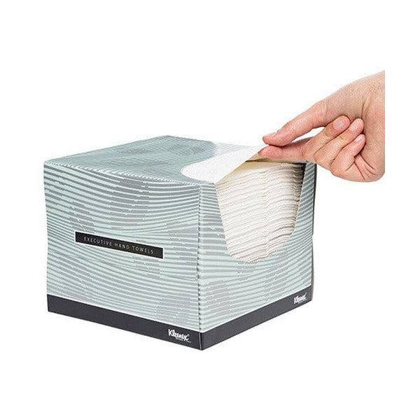 Hand drawing a white towel from the top opening of a grey green striped Kleenex Executive Hand Towels box