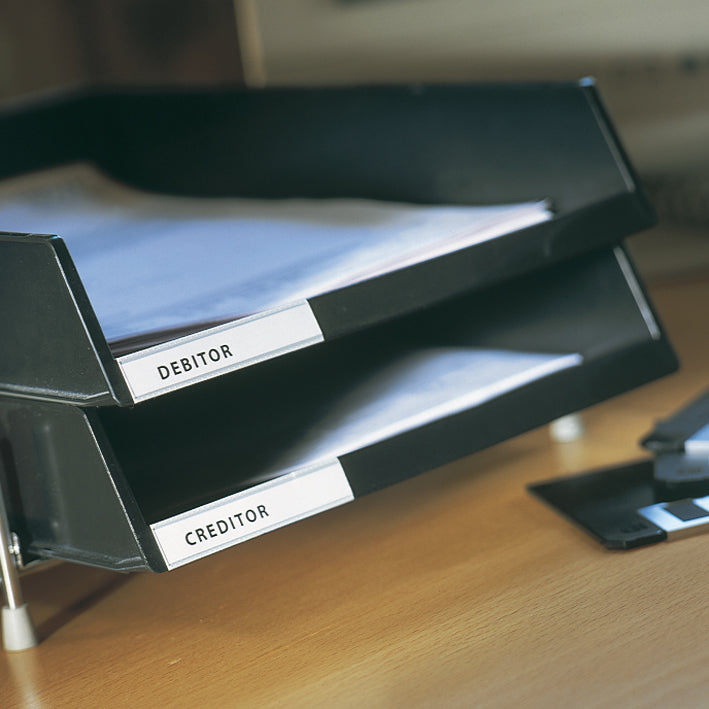 3L label holder strips with Debitor and Creditor inserts on black stacked letter trays on a desk