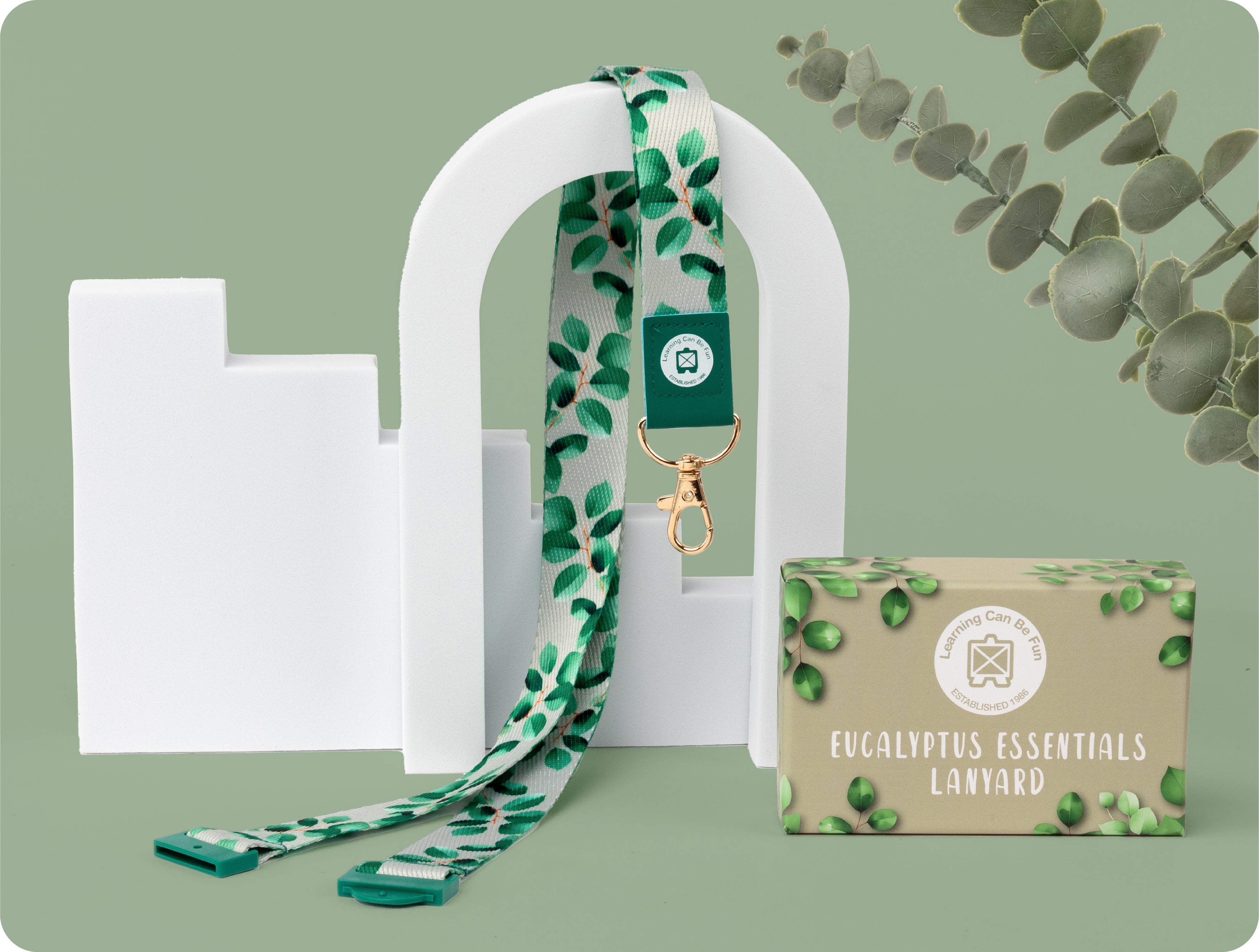 Eucalyptus Essentials lanyard in soft green with a repeating eucalyptus leaf print, shown flat with the metal clip and breakaway clasp visible.