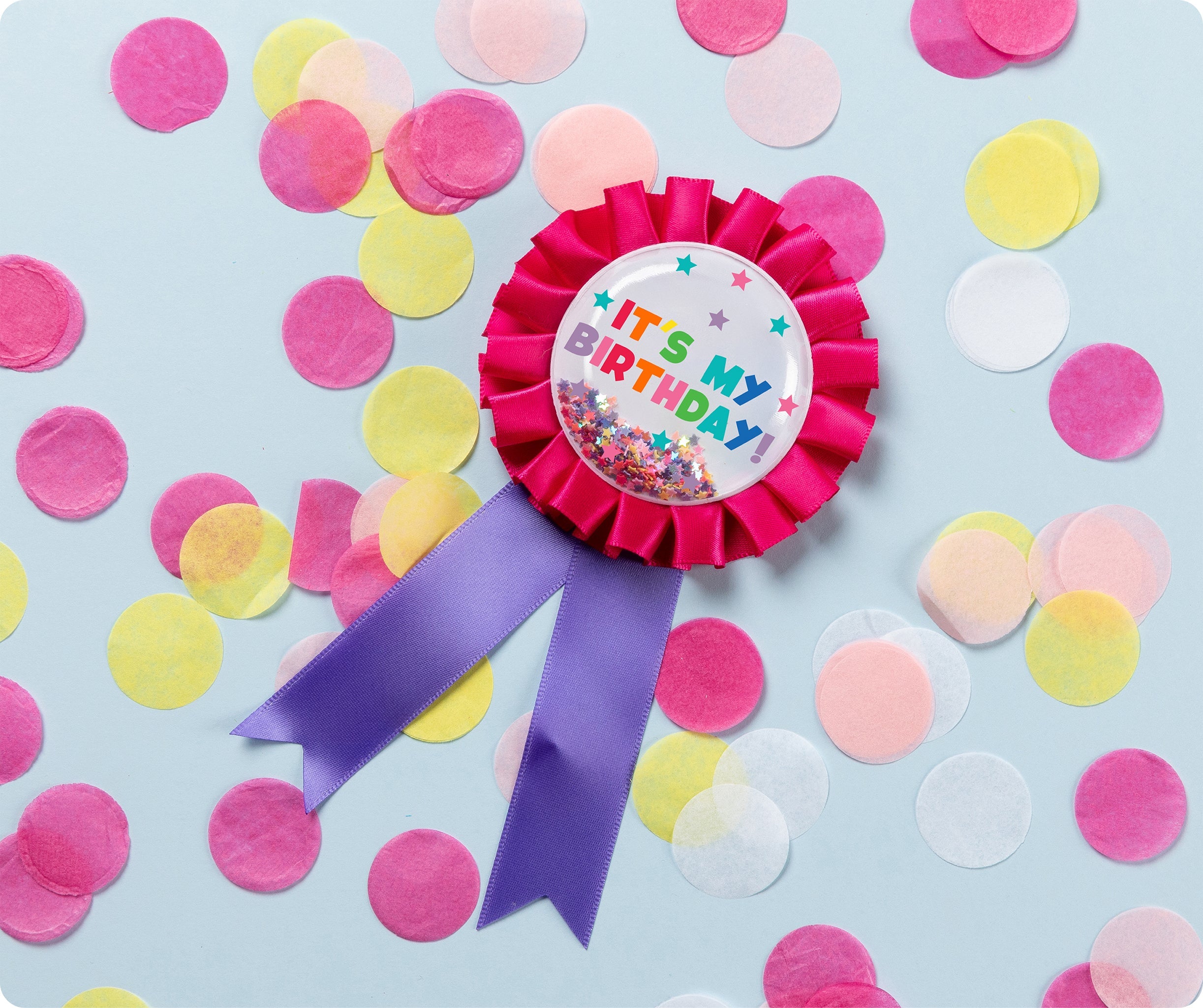 Pink Giggle and Grow birthday badge with a happy birthday message and loose metallic confetti visible inside the clear front pocket.
