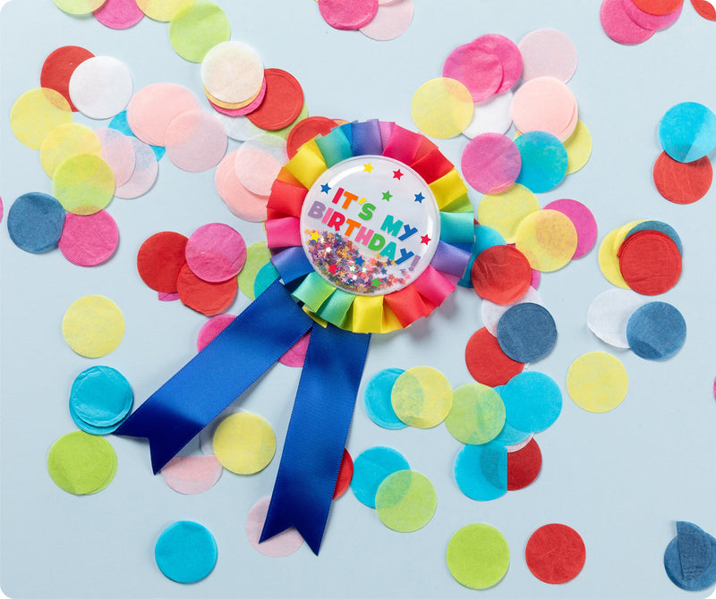 Rainbow Giggle and Grow birthday badge with a happy birthday message and multicoloured metallic confetti visible inside the clear front pocket.
