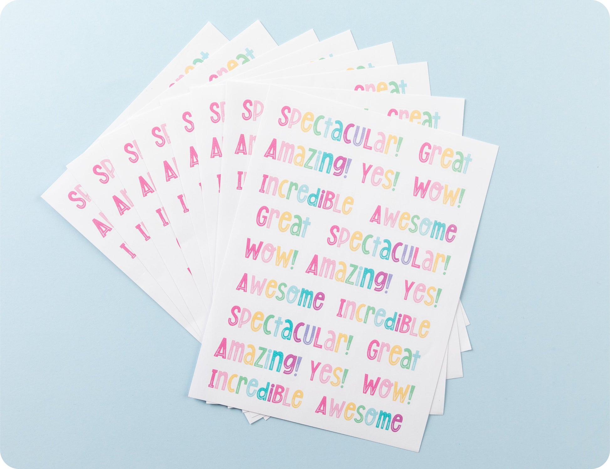 Sticker sheets from the Rainbow Shoutouts book fanned out to show the range of praise words across the sheets.
