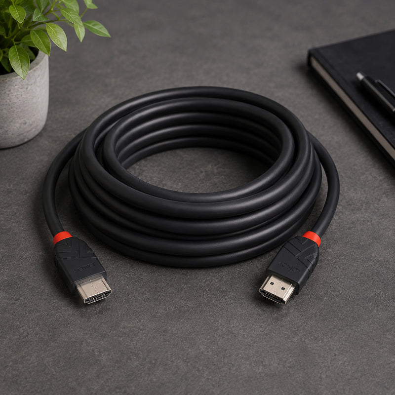 The Lindy 7.5m 8K60Hz HDMI Cable Black Line is neatly coiled on a modern desktop beside a notebook and indoor plant. Both HDMI Type A connectors are clearly visible, highlighting the flexible cable design and premium construction suitable for home entertainment and professional AV installations.