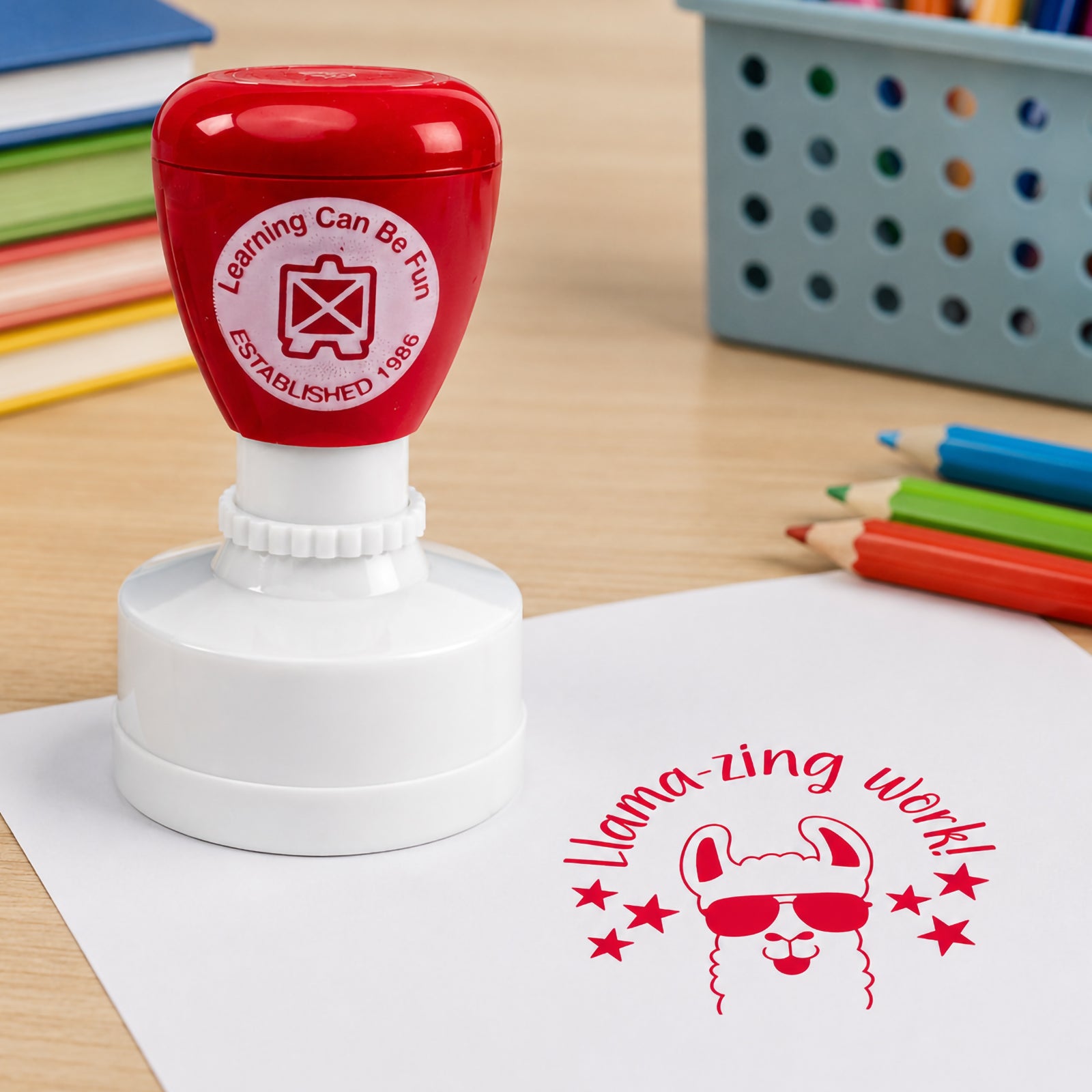 Close up classroom scene featuring the red merit stamp beside a crisp Llamazing Work impression. Colourful pencils and learning materials create an engaging educational environment focused on positive reinforcement.