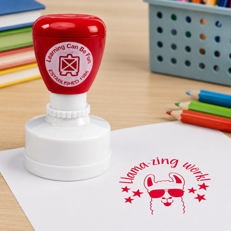 Close up classroom scene featuring the red merit stamp beside a crisp Llamazing Work impression. Colourful pencils and learning materials create an engaging educational environment focused on positive reinforcement.