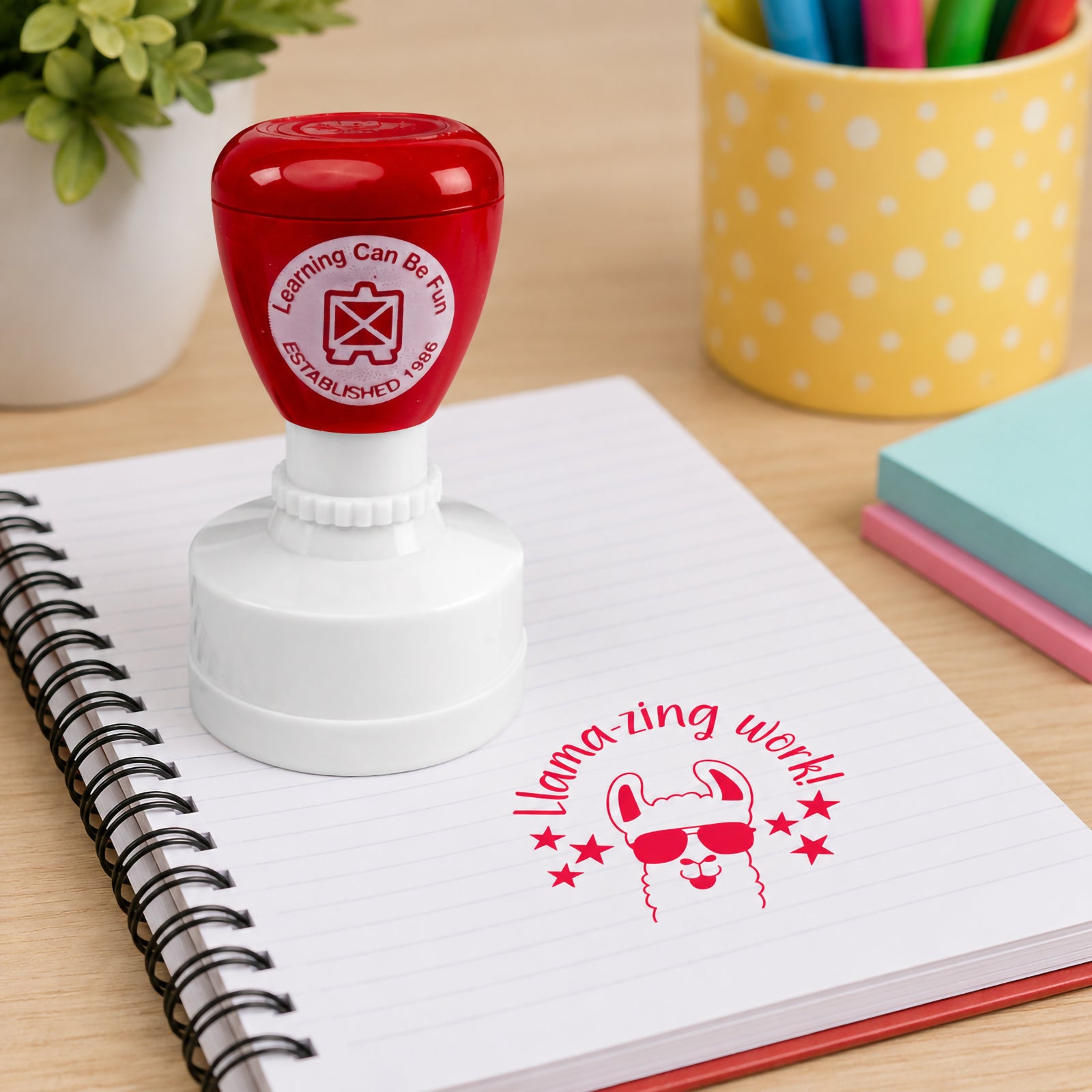 Self inking Llamazing Work reward stamp positioned on a spiral notebook with a bold red llama design. The playful sunglasses wearing llama adds excitement and encouragement to classroom feedback and recognition.