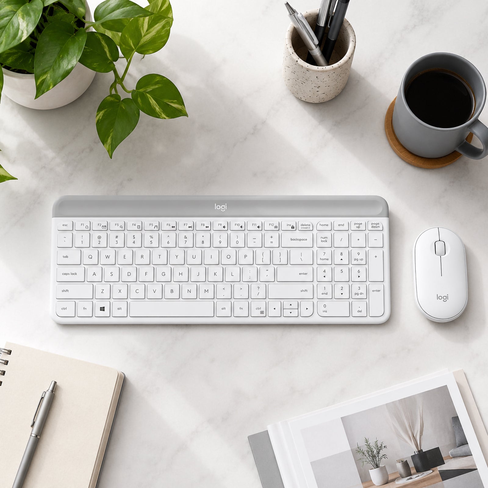 Top view of the Logitech MK470 Slim Wireless Keyboard and Mouse Combo Off White neatly arranged on a marble desktop beside a notebook, coffee mug, stationery and indoor plant, highlighting the full size keyboard layout and matching wireless mouse.