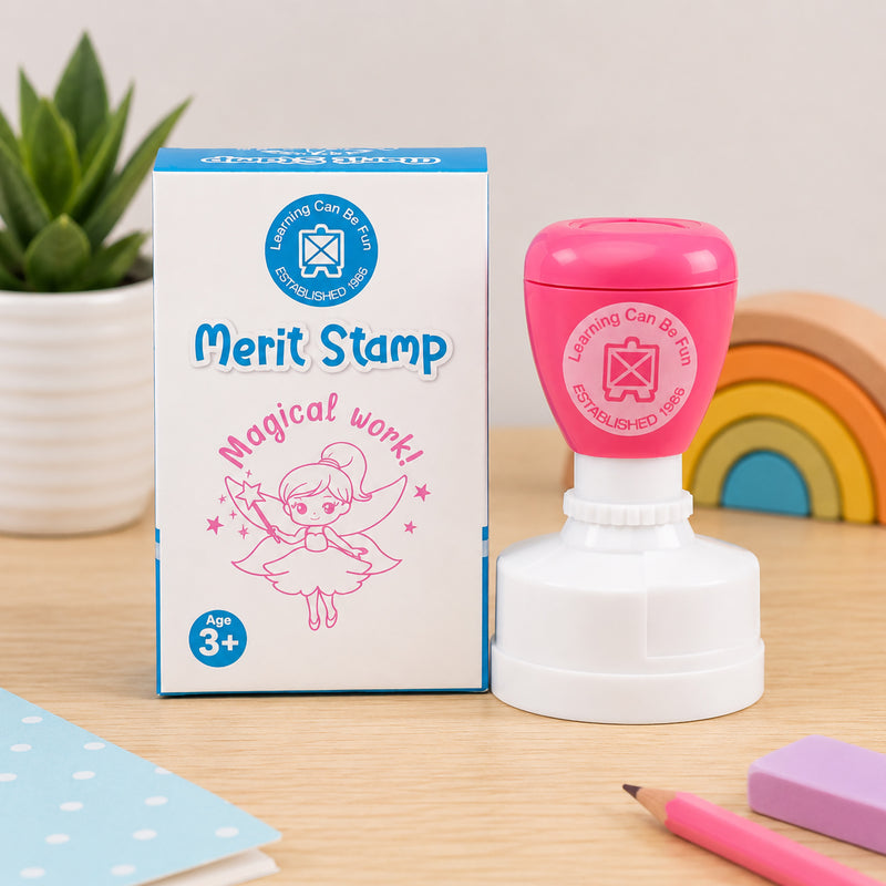 Retail packaging and the merit stamp are presented together in a classroom setting. The packaging showcases the fairy artwork and Magical Work! message, highlighting the product's playful design and suitability for educational reward systems.