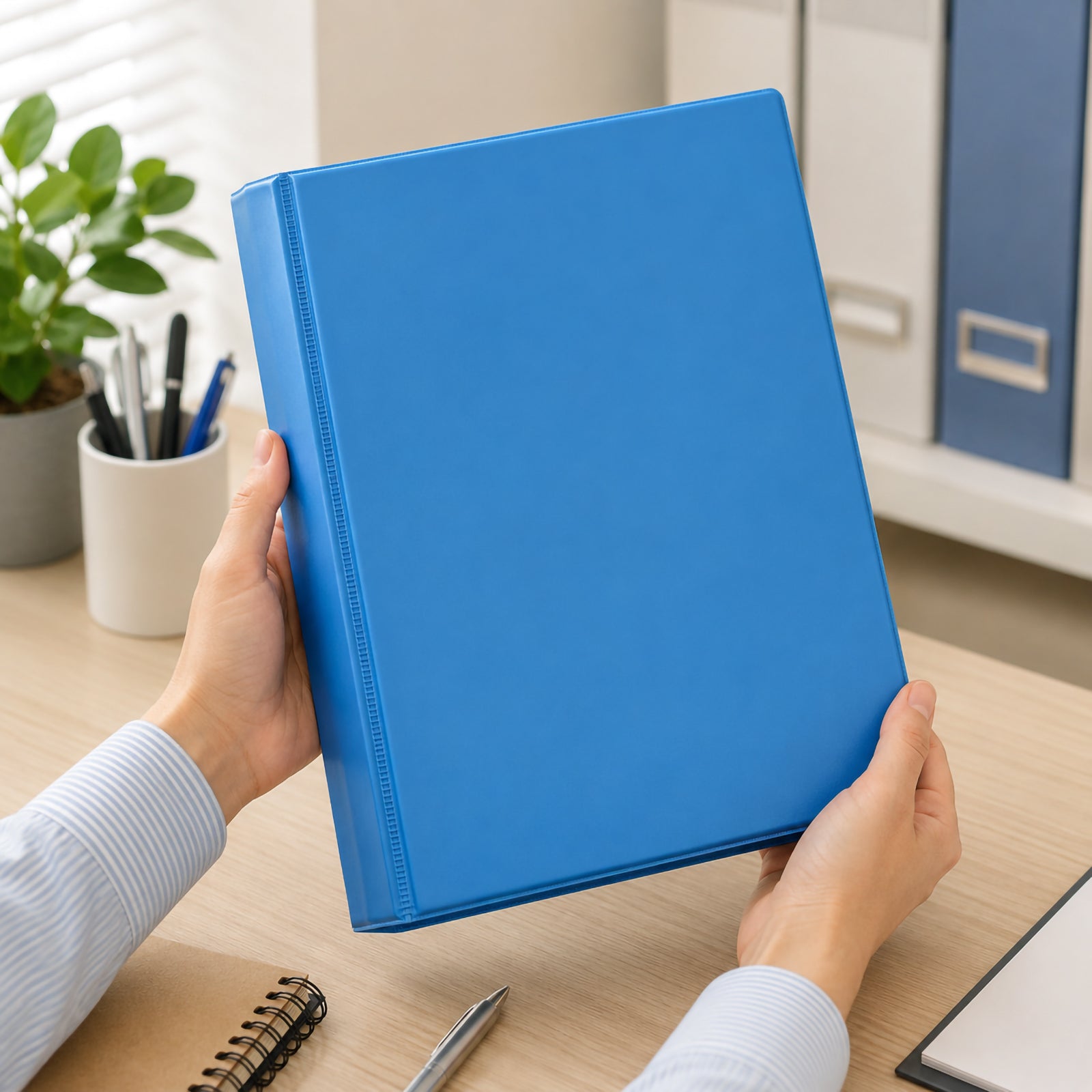 Hands holding the Marbig Clearview A4 50mm 4D Ring Marine Insert Binder in a modern office workspace, demonstrating comfortable everyday handling while organising reports, presentations and important business documents.