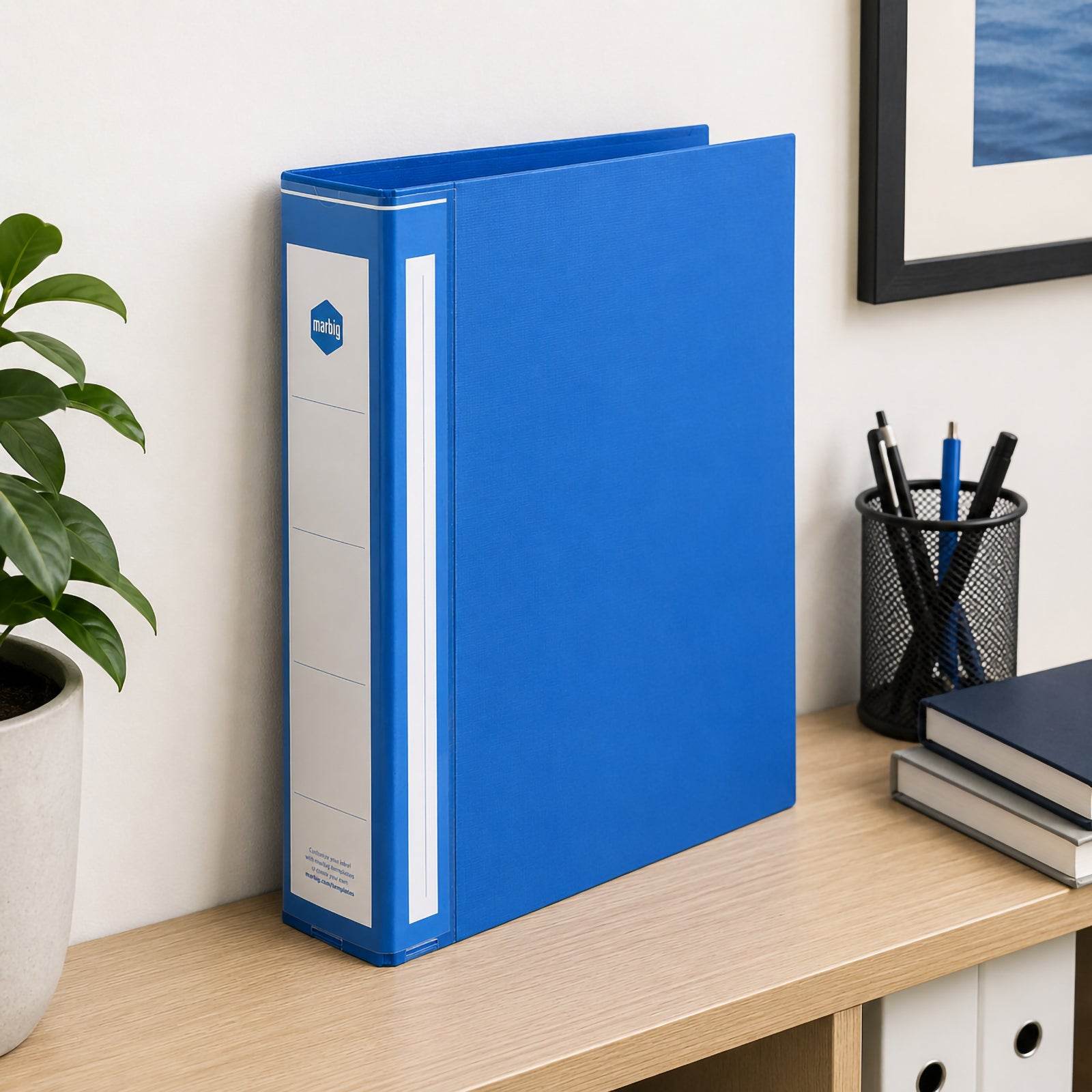 Marbig Deluxe Ring Binder A4 50mm 3D Ring PE Blue displayed upright on an office desk beside stationery and storage accessories, demonstrating its clean design and suitability for everyday filing.
