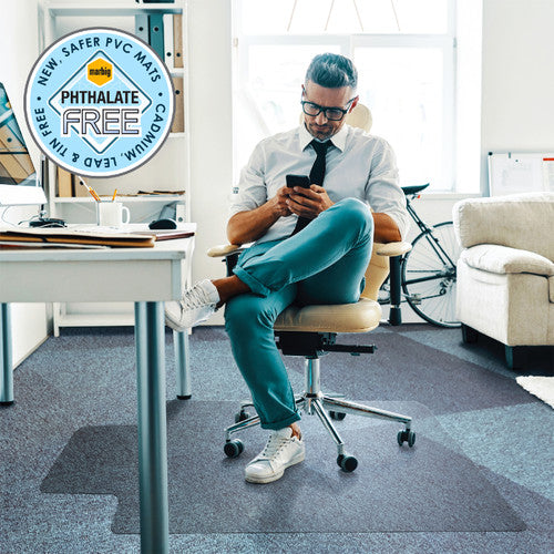 Man seated on an office chair working on his phone, with the chair on a clear Marbig keyhole chairmat over blue carpet