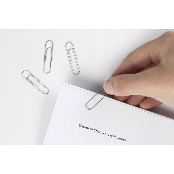 Hand sliding a silver Marbig 33mm paper clip onto the corner of a printed page, with two loose clips on the desk
