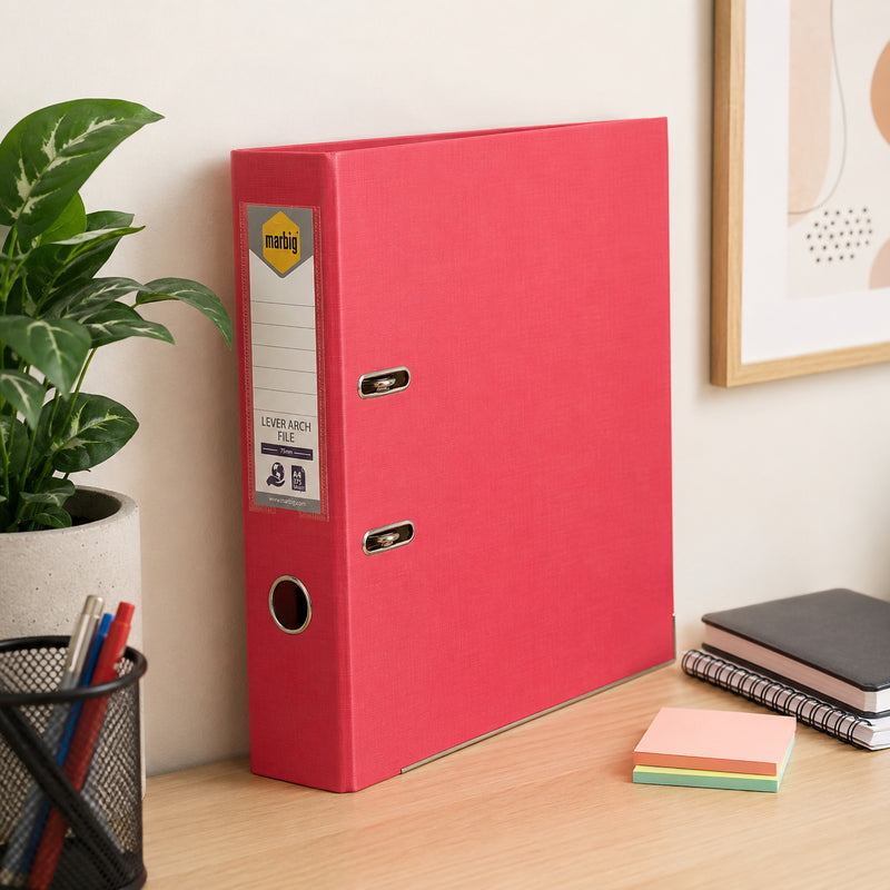 Marbig Lever Arch File A4 PE Coral standing upright on an office desk beside notebooks, plants and stationery, demonstrating its attractive colour, sturdy construction and organised office storage.