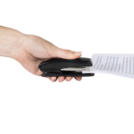A hand holding the black Marbig 90400B stapler around the edge of a few printed sheets, showing its size in use