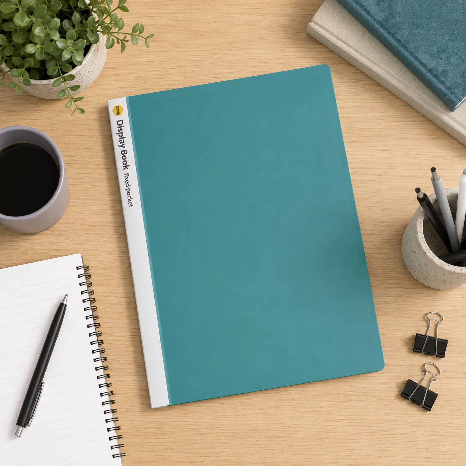 Top view of the Marbig A4 20 pocket green display book resting on a wooden desk beside a notebook, coffee cup, stationery holder, binder clips and decorative plant. The vibrant green cover and customisable white spine create an organised and professional workspace.