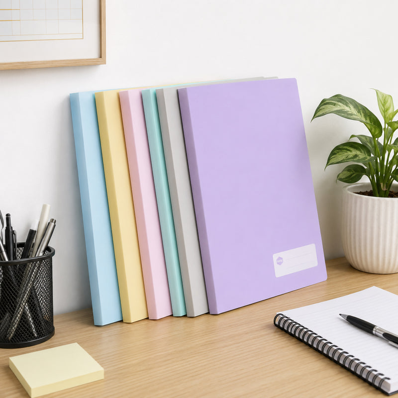 Six pastel coloured Marbig A4 display books standing upright against an office wall beside stationery, a notebook and indoor plant. The attractive pastel assortment creates a modern workspace while showcasing practical document storage and presentation.