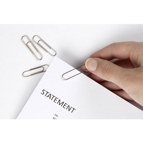Fingers sliding a silver Marbig paper clip onto the corner of a printed statement, with more clips on the desk