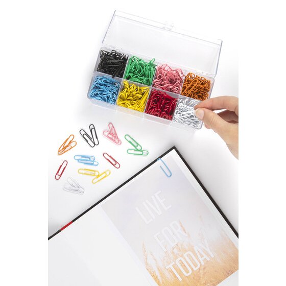 Hand taking a white clip from an open Marbig assorted paper clip container beside a notebook, with coloured clips on the desk