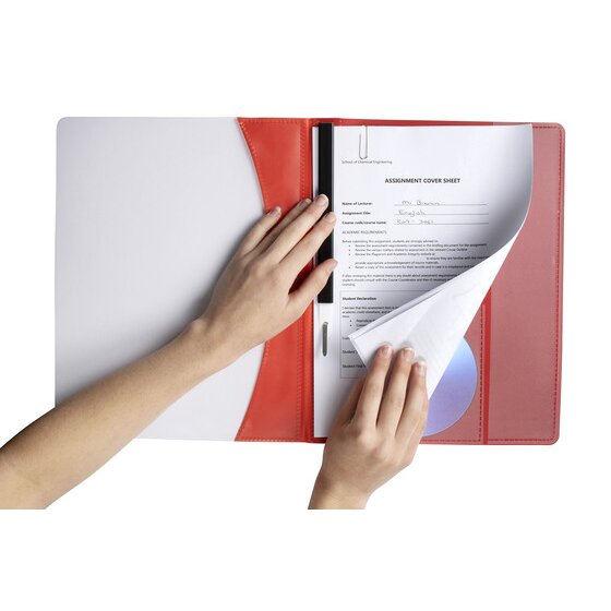 Hands turning punched pages held under the slide bar of a red Marbig Premier flat file, a disc visible in the back pocket