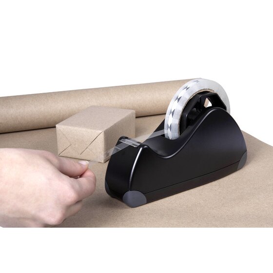 Hand drawing tape from a Marbig Pro Series large black dispenser beside a small parcel wrapped in brown kraft paper on a paper roll