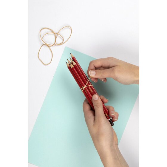 Hands wrapping a thin natural rubber band around a bundle of red pencils on a pale blue sheet of card