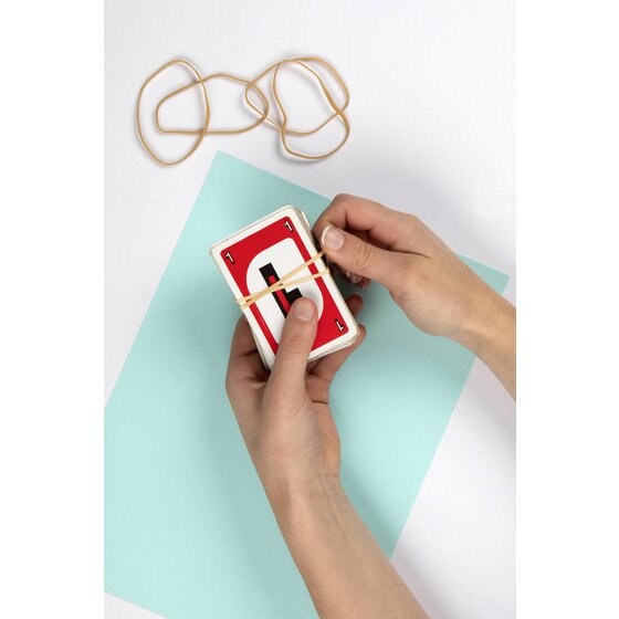 Hands slipping a natural rubber band around a deck of red playing cards over a pale blue sheet of card