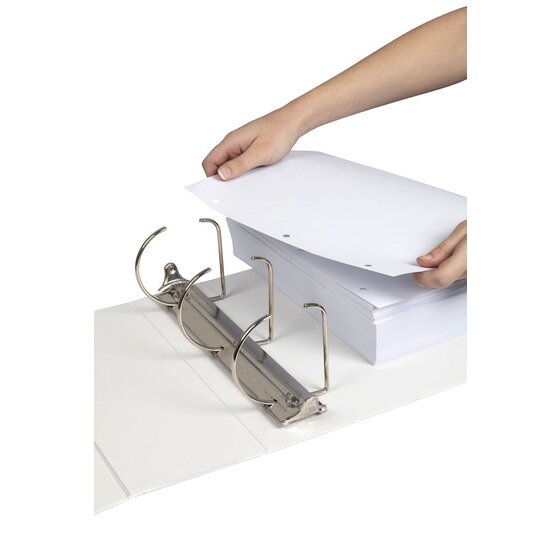 A hand lowering a thick stack of three hole punched white paper onto the open three slanted D ring mechanism of a white Marbig Titan insert binder lying flat on a white surface.