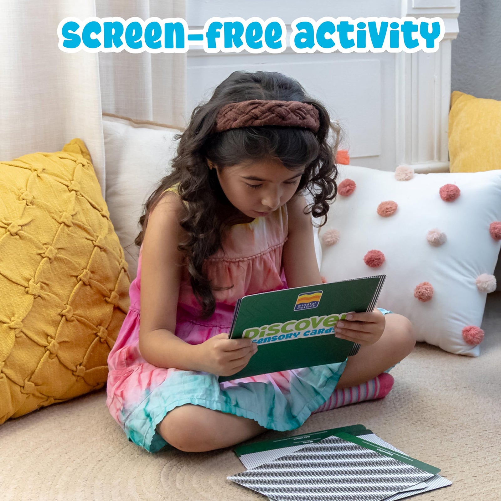 Young child sitting on the floor exploring the Mindful Motions sensory cards independently in a calm and relaxing learning environment.