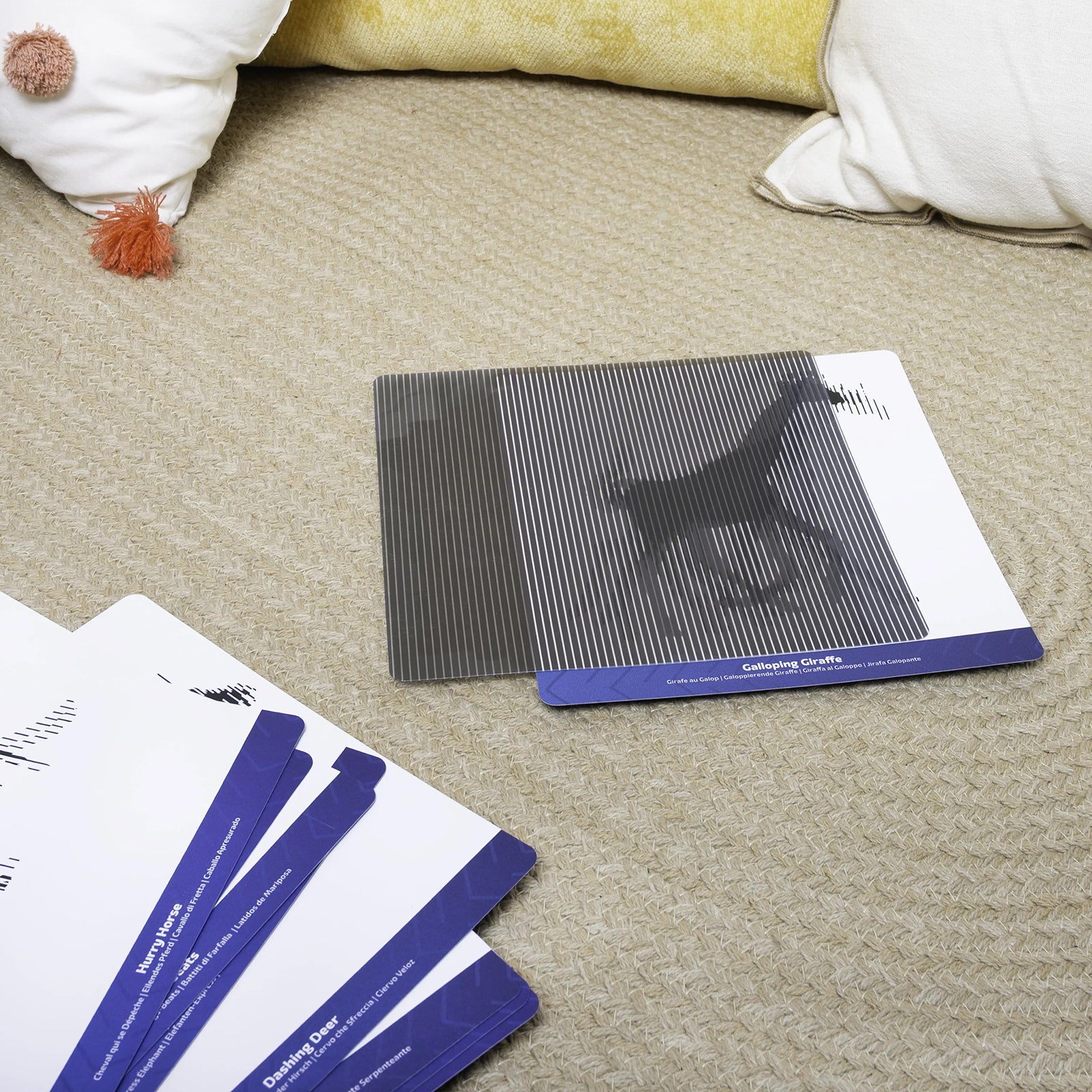 Galloping giraffe illusion sensory card displayed on a soft floor mat with additional animal themed sensory cards arranged nearby for mindful exploration activities.