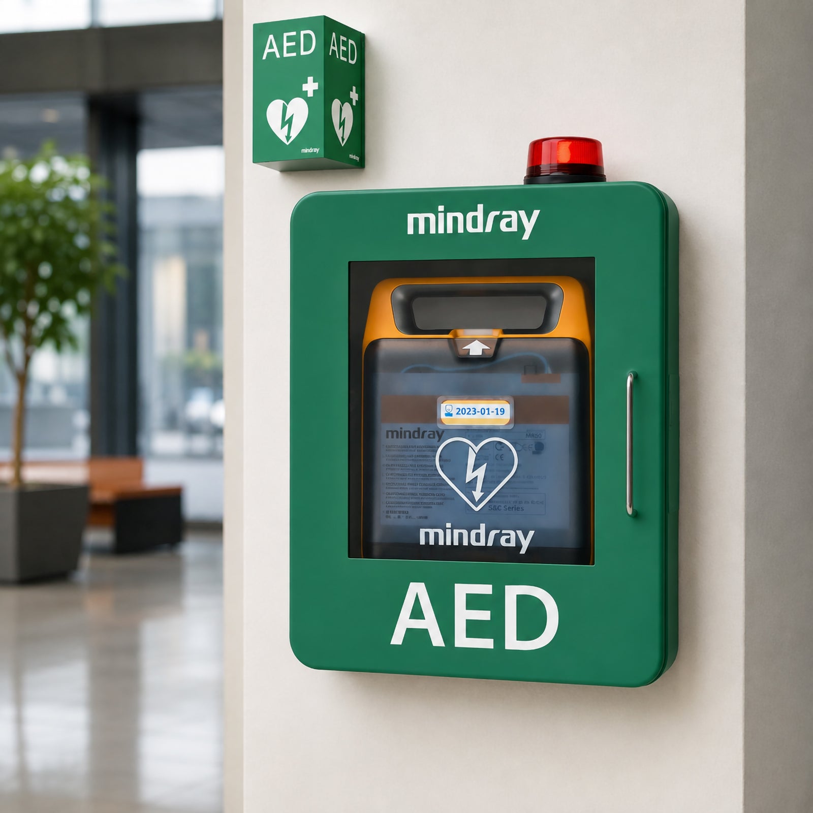 Mindray C2 Fully Automatic Defibrillator with 4G stored inside a green wall mounted AED cabinet in a modern public building. Clear AED identification and highly visible positioning demonstrate a practical public access installation for workplaces and community facilities.