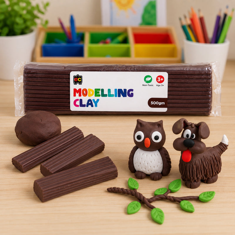 Educational Colours 500gm brown modelling clay displayed on a wooden craft table with handmade clay owl, dog, and leafy branch creations in a bright creative workspace.