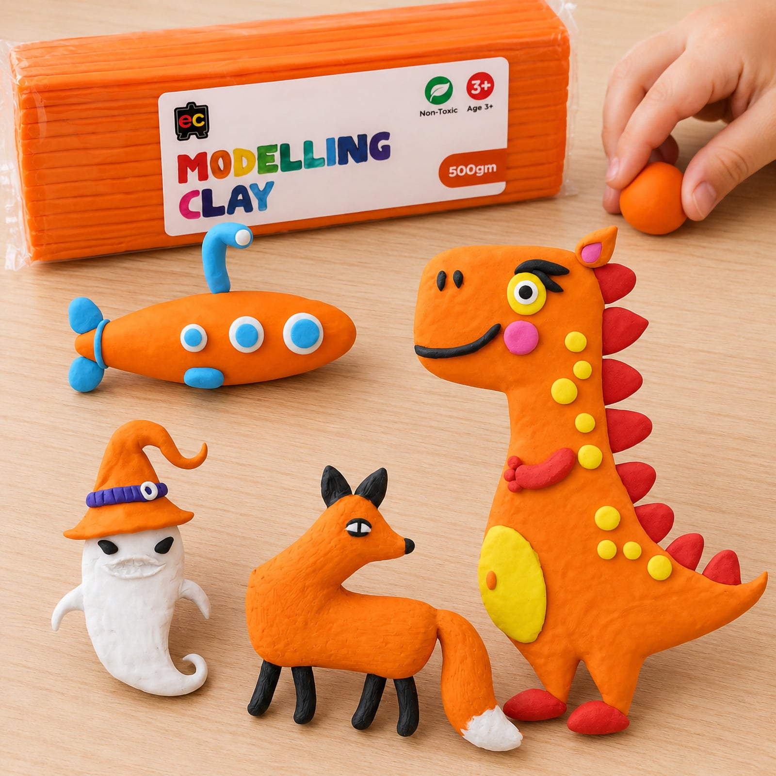Overhead view of orange modelling clay creations including a dinosaur, submarine, fox, and ghost arranged around Educational Colours Modelling Clay 500g Orange packaging.