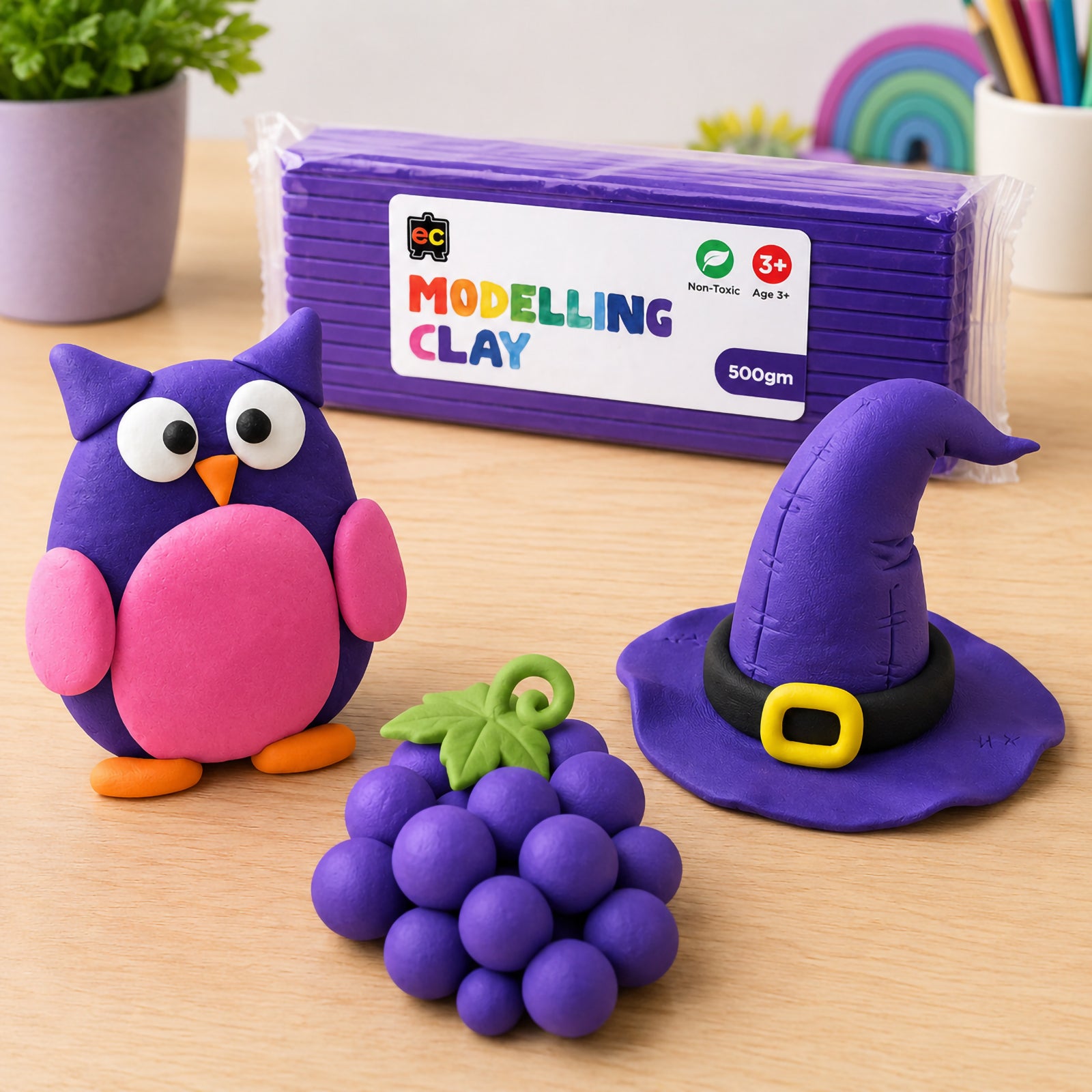 Purple modelling clay craft scene featuring colourful owl, witch hat, and grape clay models beside Educational Colours Modelling Clay 500g Purple packaging.