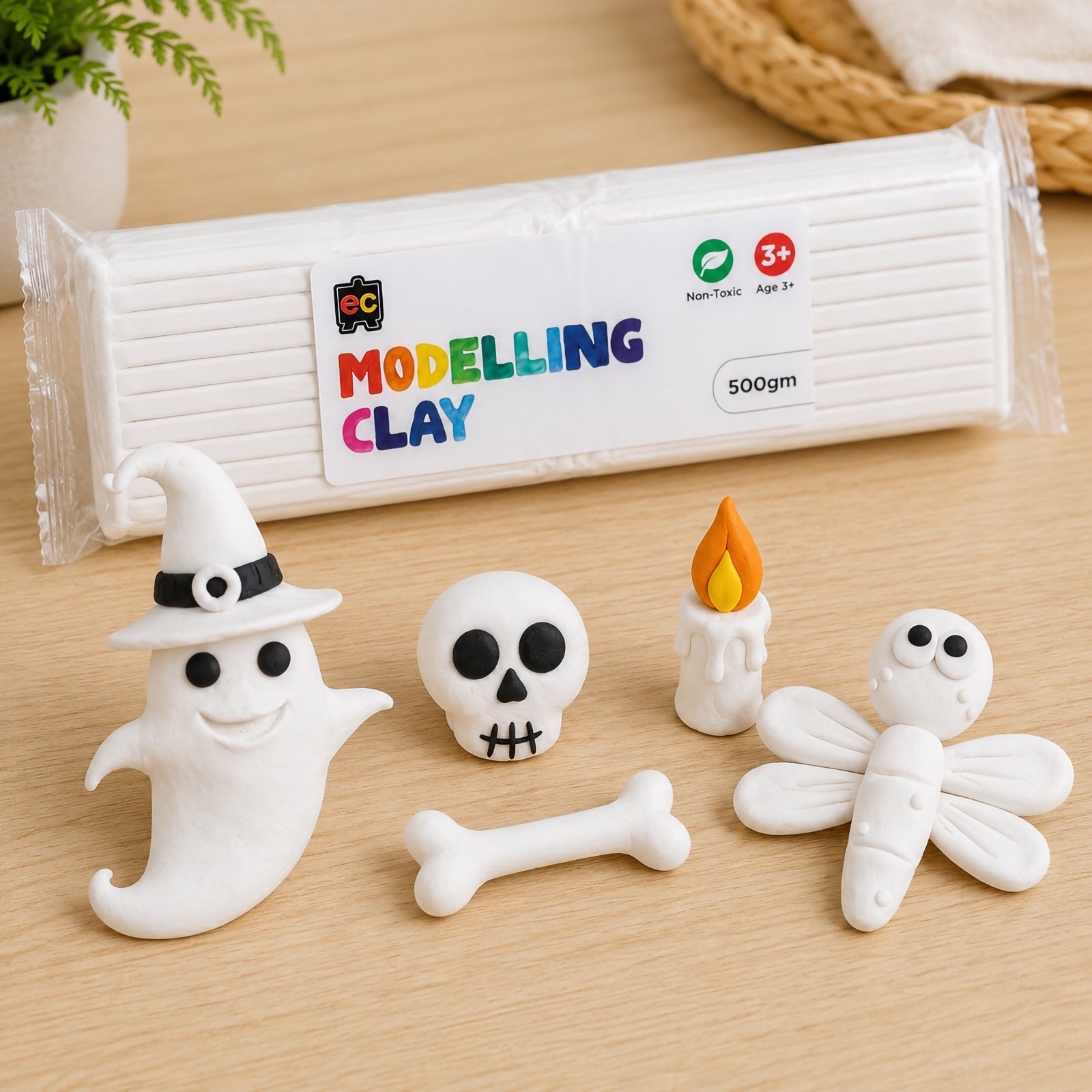 Educational Colours white modelling clay pack with rolled clay sticks and handmade ghost, skull, and dragonfly sculptures arranged on a light wood surface.