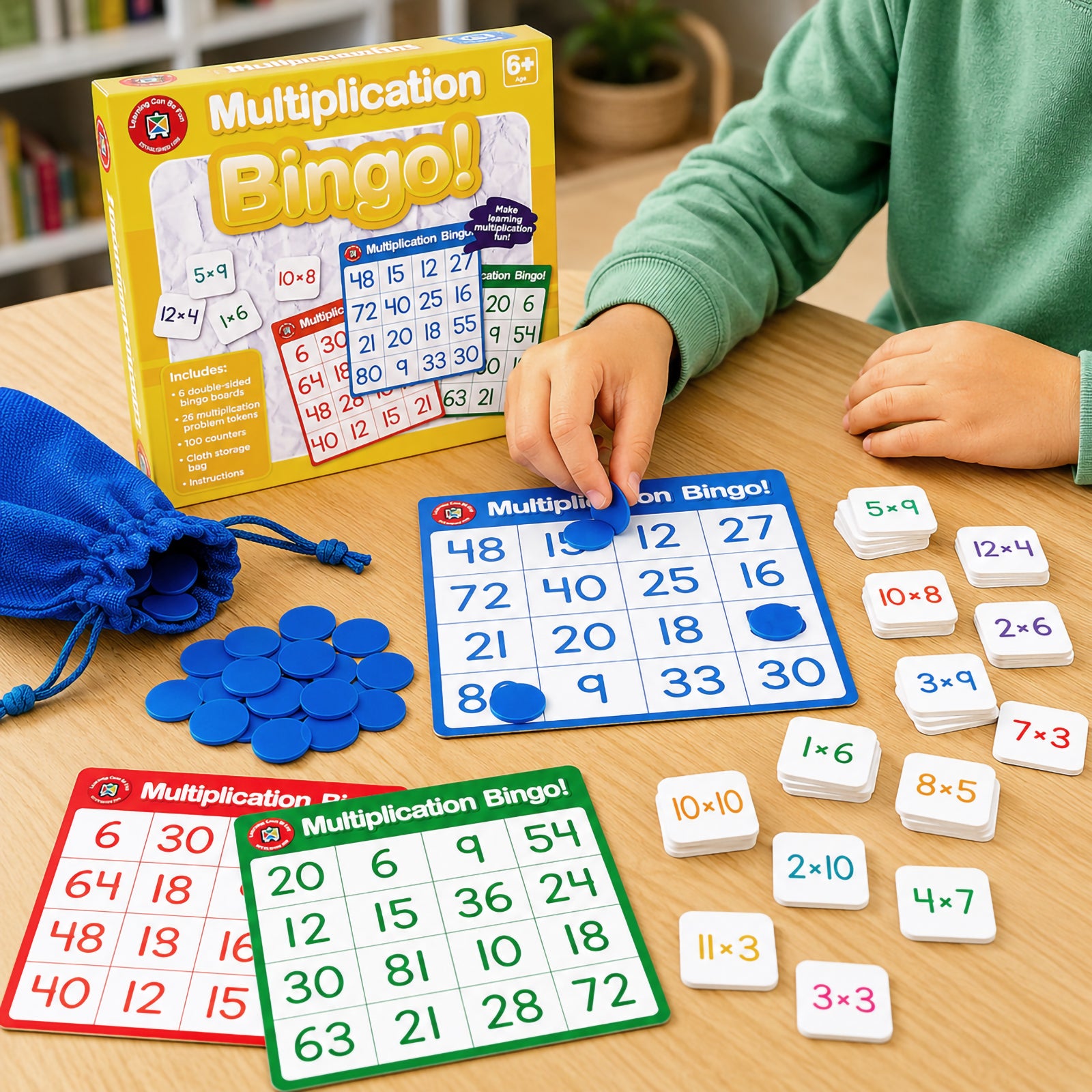 Complete Multiplication Bingo educational game set featuring retail packaging, bingo boards, multiplication problem tokens, counters and storage bag. The image highlights all included components designed to support multiplication learning through interactive play.