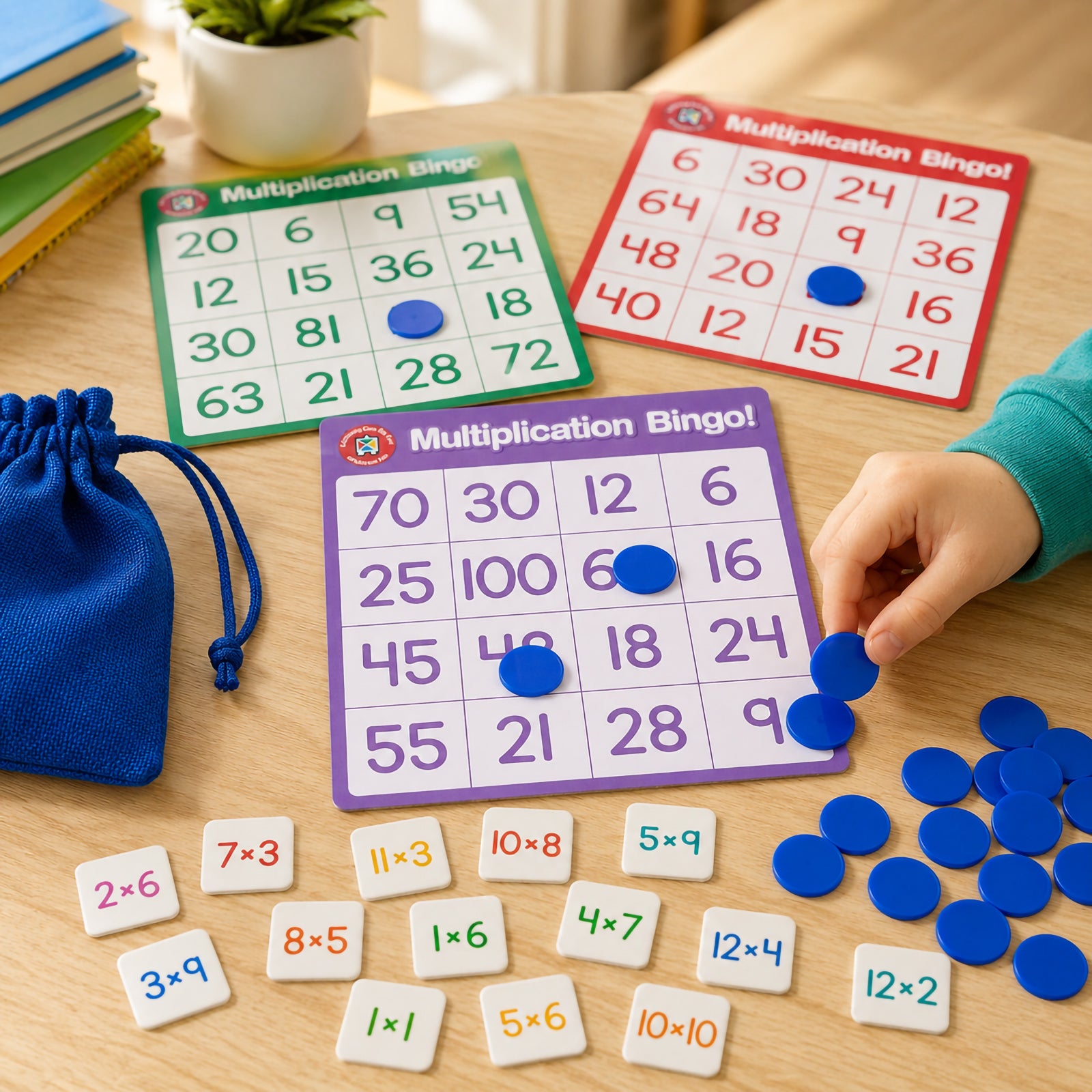 Multiple Multiplication Bingo boards displayed on a classroom table with counters, multiplication tokens and a drawstring storage bag. A child places counters on the board while practising times tables, showcasing collaborative learning and numeracy skill development.