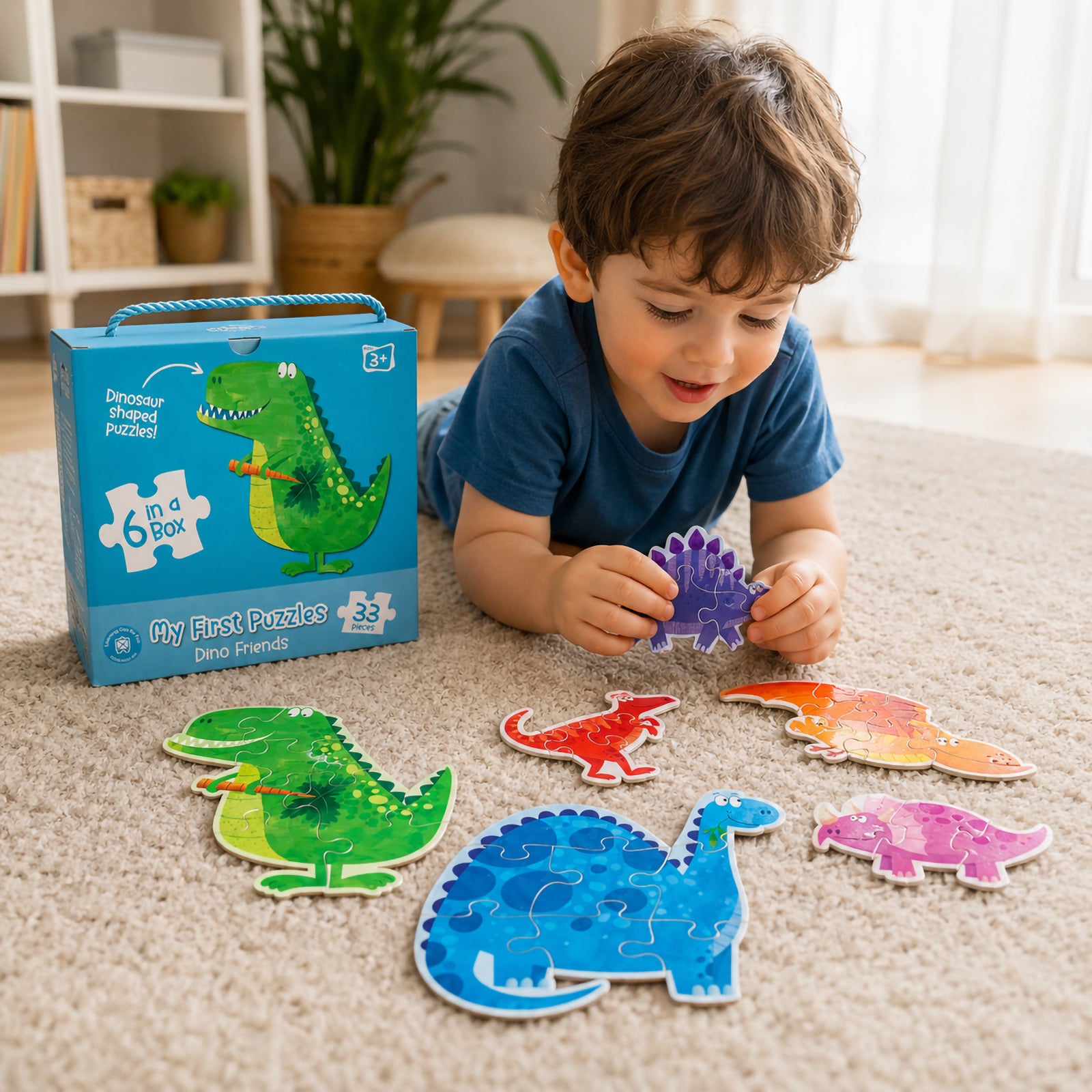 Young child playing with the My First Puzzles Dino Friends set on a soft carpet, assembling colourful dinosaur shaped puzzles while the bright blue carry case is displayed alongside the completed dinosaur characters.