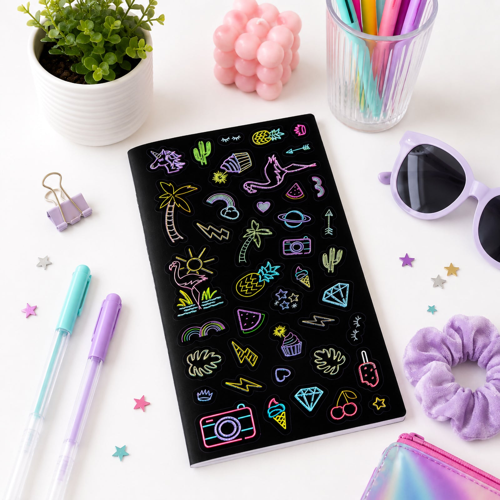 Full sticker sheet displayed on a clean desktop with pastel pens, sunglasses and decorative accessories. The collection features a fun mix of tropical, celestial and trendy lifestyle icons.