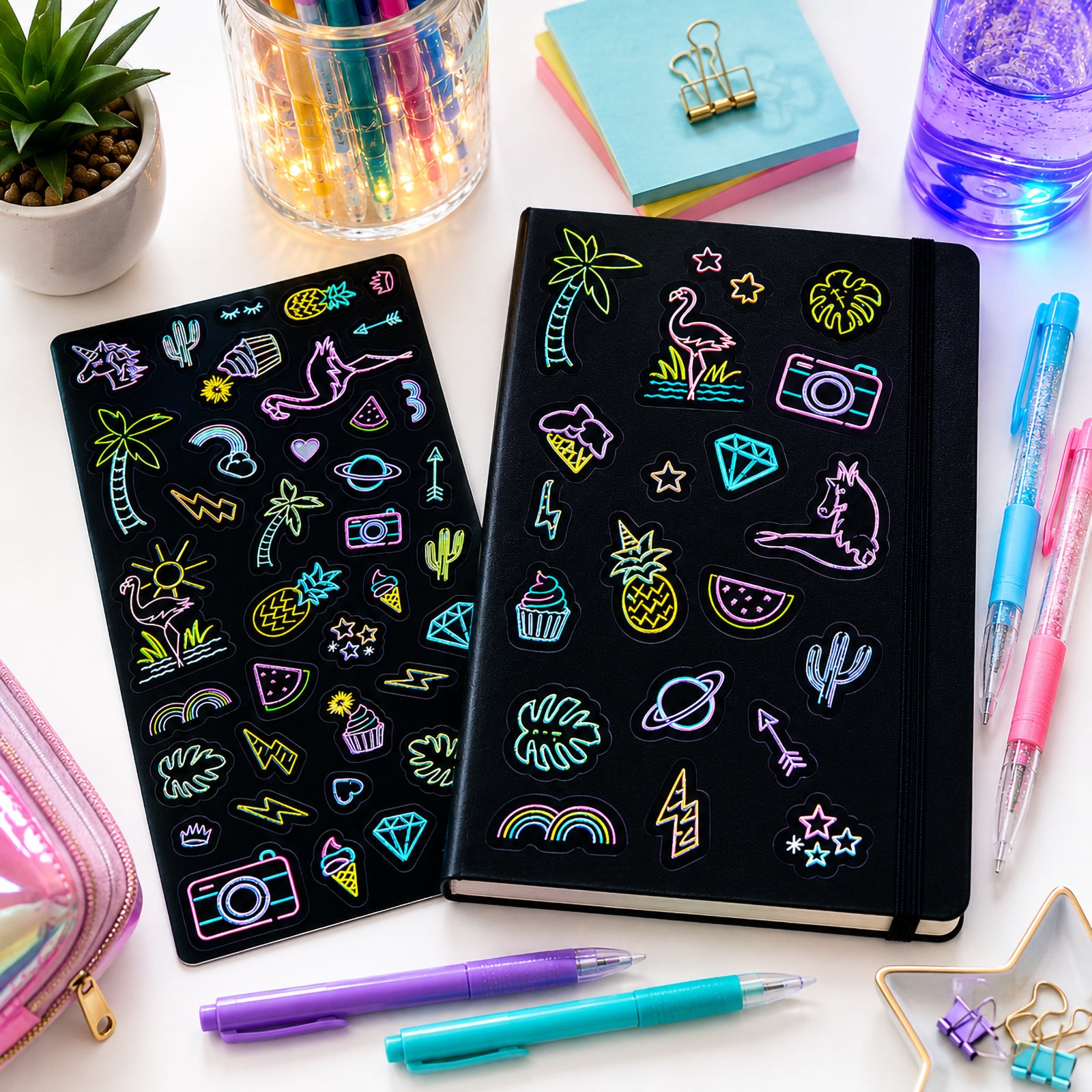 Neon Nights glow in the dark stickers displayed beside a notebook and colourful stationery. Bright tropical and lifestyle themed designs including flamingos, cameras, pineapples and rainbows showcase creative decorating possibilities.