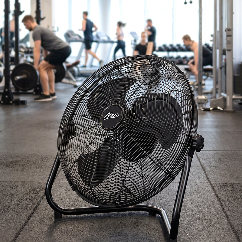 Nero 50cm black industrial floor fan standing on a gym floor with people training in the background