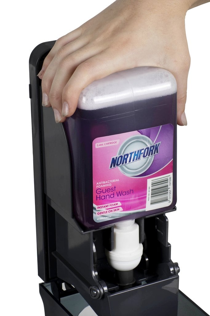 Hand sliding a Northfork Guest foaming hand wash 1L cartridge into a black dispenser, from a carton of 6