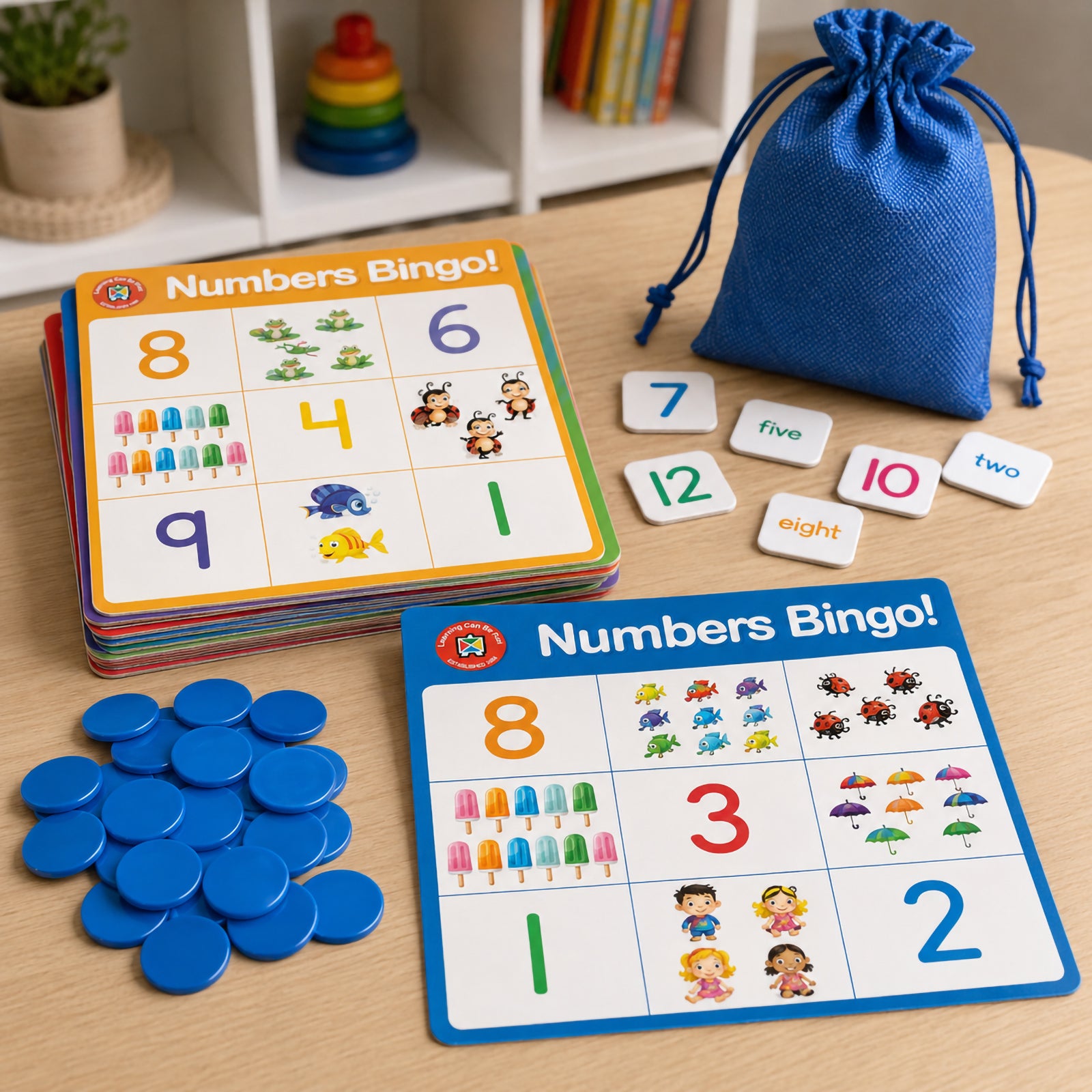 Numbers Bingo components displayed on a table including colourful double sided bingo boards, number tokens, counters and a blue drawstring storage bag. The educational game demonstrates number recognition activities using numerals, number words and picture counting representations for young learners.