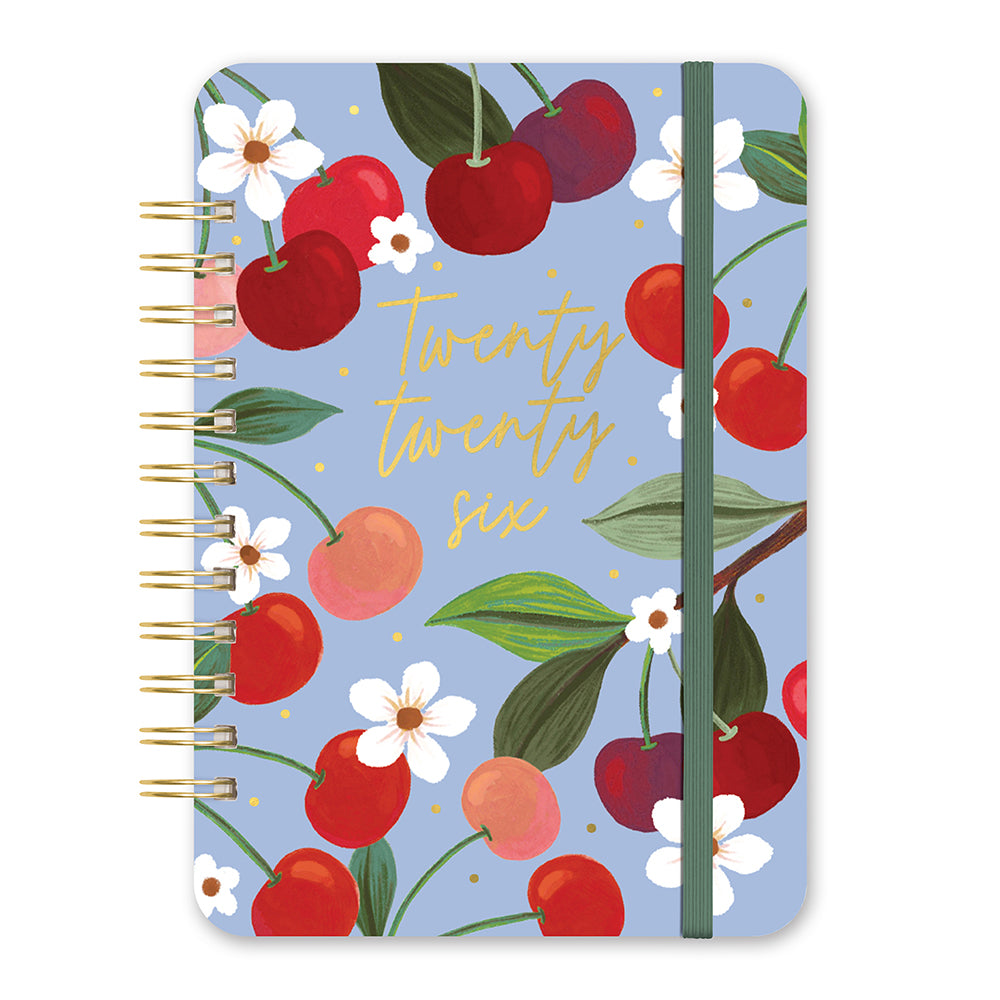 Orange Circle 2026 Do It All diary Fruit and Flora, front cover: cherries, peaches and white blossom on periwinkle blue with gold "twenty twenty six" script and a green elastic band