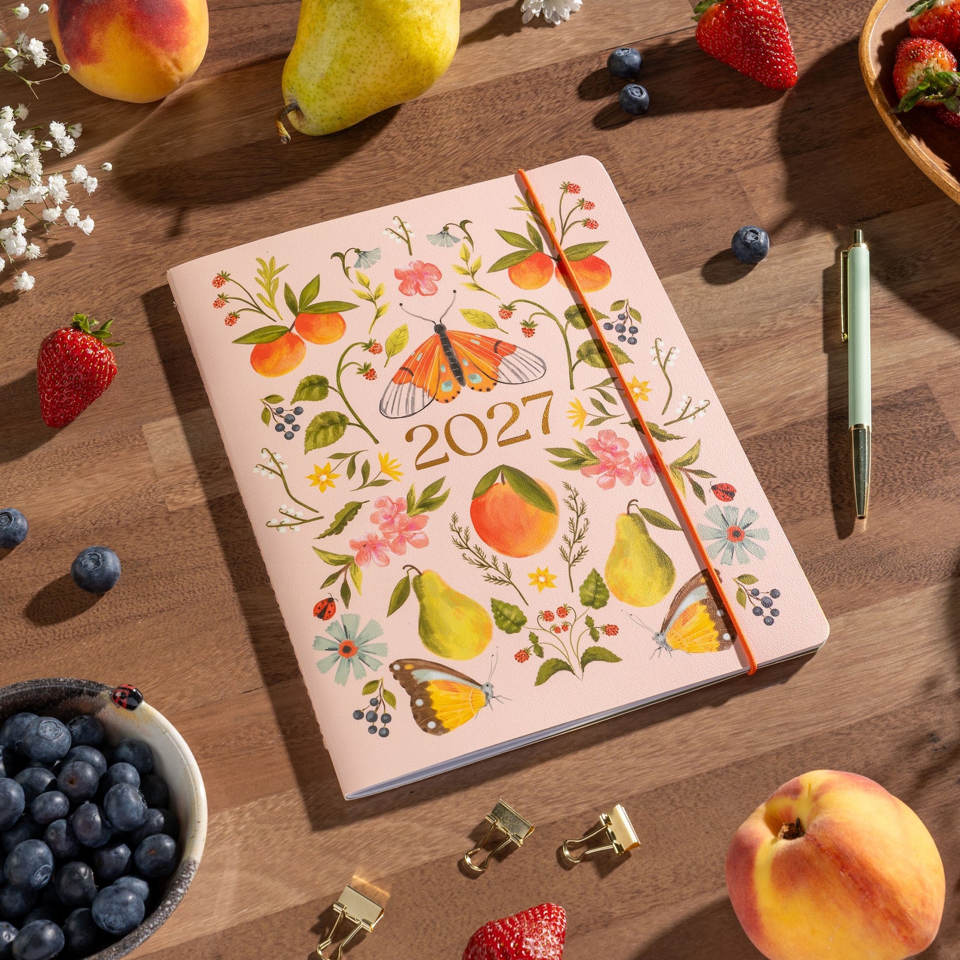 Orange Circle 2027 Just Right Diary 191 x 248mm Month To View Fruit And Flora shown from a further angle, the Fruit And Flora design, a bright botanical mix of fruit and flowers, showing the cover corners and closure detail.