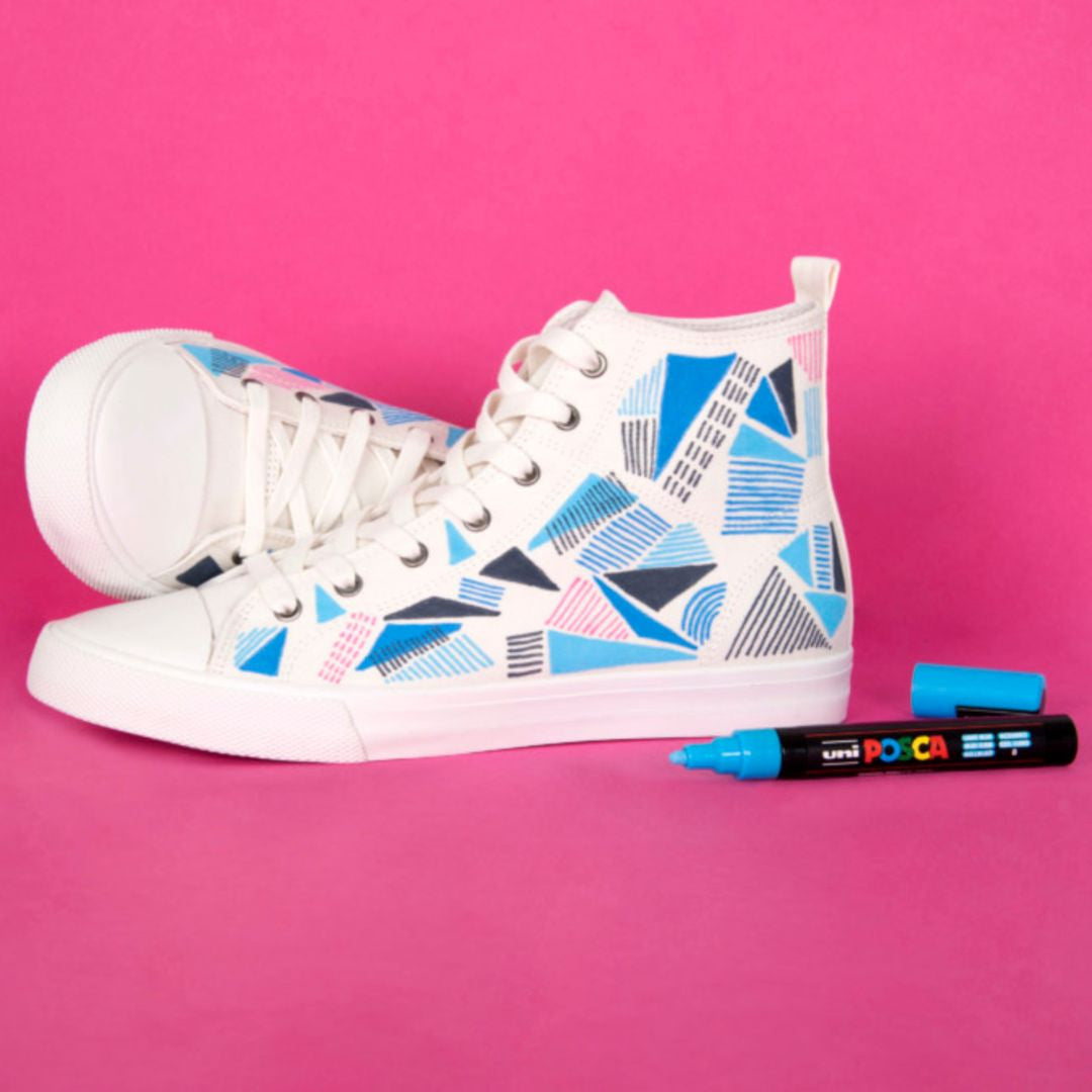 Sneakers decorated with geometric designs using POSCA PC-5M paint markers on a bright background
